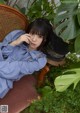 A woman sitting on a chair in front of a plant.