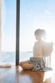 A woman sitting on the floor in front of a window.