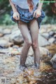 A woman in a plaid skirt is standing in a stream.