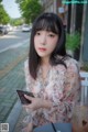 A woman sitting at a table with a drink and a cell phone.