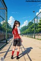 A girl in a red and white shirt and black shorts standing on a soccer field.